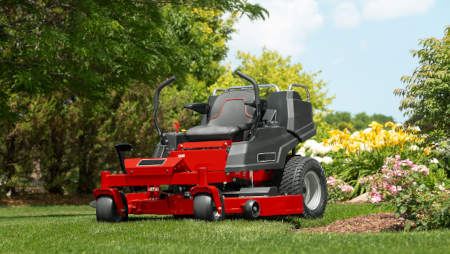 Red riding lawn mower on a lush green yard with vibrant flowers and trees, showcasing professional landscaping services
